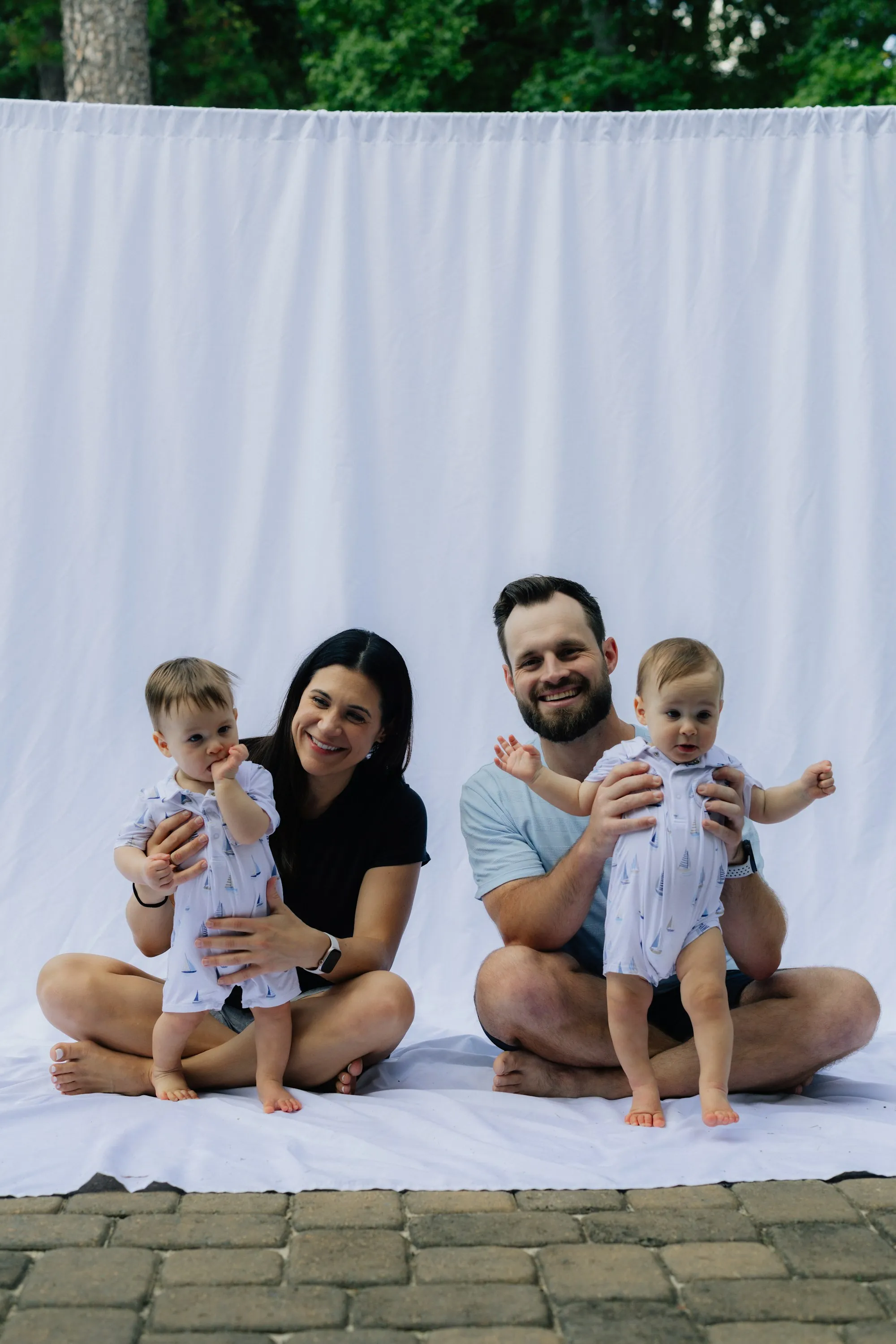 Smiling parents each holding one of their twin babies