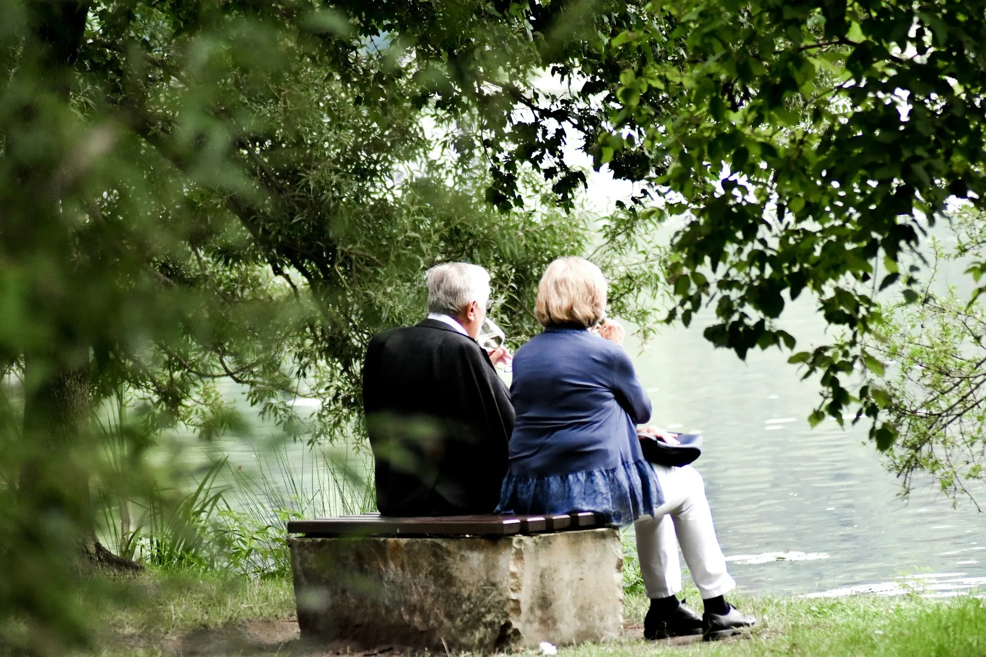 Senior couple sitting on a bench beside a lake
